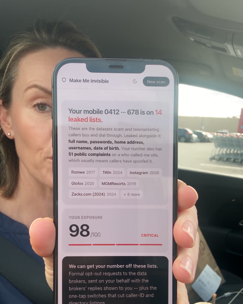 Woman in a car holding up a phone showing her Make Me Invisible result